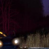 Abandoned suitcase on snowy road lit by approaching car